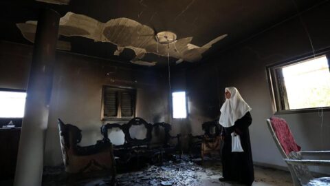 A Palestinian woman inspects a house burned during Israeli settlers' attack the day before in the town of Jit in Qalqilya, northern West Bank, on Aug. 16, 2024.