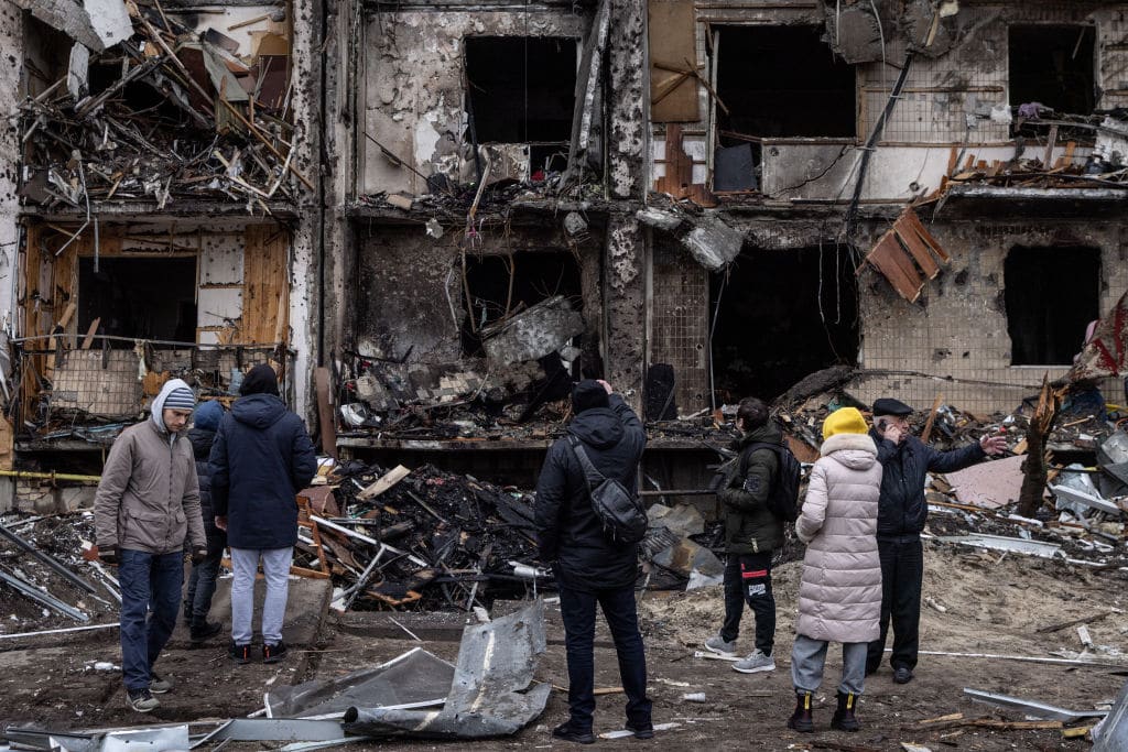 People look at the exterior of a damaged residential block hit by an early morning missile strike on February 25, 2022 in Kyiv, Ukraine. Yesterday, Russia began a large-scale attack on Ukraine, with Russian troops invading the country from the north, east and south, accompanied by air strikes and shelling. The Ukrainian president said that at least 137 Ukrainian soldiers were killed by the end of the first day. (Photo: Chris McGrath/Getty Images)