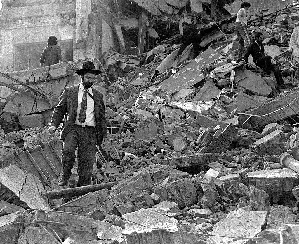 A man walks over the rubble left after a bomb exploded at the Argentinian Israeli Mutual Association (AMIA in Spanish) in Buenos Aires, 18 July 1994.