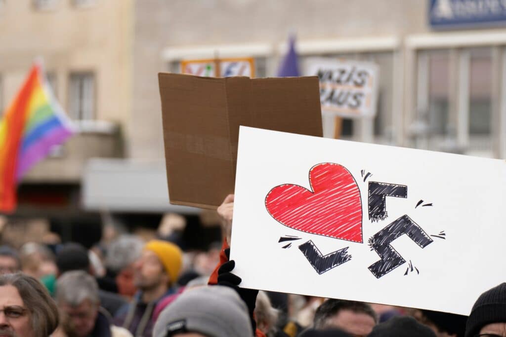 A sign of a swastika being destroyed by a heart at an anti-hate rally (Photo by Mika Baumeister).